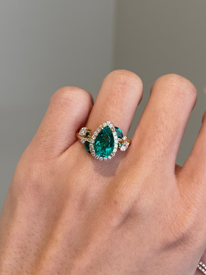 Hand wearing a ring with a green gemstone on a neutral background